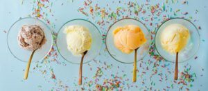 What is the best ice cream maker? a detailed review image 5 jpeg 4 ice cream scoops in glass dishes with wooden spoons and sprinkles on blue background frosted fusions