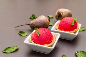 Homemade-Beetroot-Ice-Cream-Naturally-Sweet-Vibrant-image-5-scoops-of-fresh-beetroot-ice-cream-in-white-dishes-with-2-raw-beetroot-and-fresh-geeen-leaves-scattered-frosted-fusions