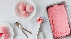 Homemade-Rhubarb-Ice-Cream-A-Truly-Tantalisingly-Tangy-Treat-image-6-tray-and-plates-of-rhubarb-ice-cream-with-silver-spoons-and-ice-cream-scoops-top-view-frosted-fusions