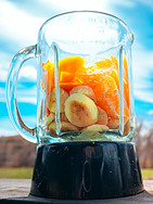 Blender-vs-Food-Processor-What-are-the-Differences-image 1-blender with black base filled with fruit and a blue sky background frosted-fusions