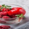 Berrylicious-Homemade-Raspberry-Sorbet-featured-image-200x600w-raspberry-sorbet-in-glass-dish-with-fresh-raspberries-and-sprigs-of-green-leaves-frosted-fusions