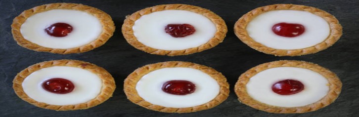 Cherry-Bakewell-Bliss-A-Delectably-Classic-Cherry-Bakewell-Homemade-Ice-Cream-featured-image-201x615w-jpeg-6-cherry-bakewells-lined-up-dark-background-frosted-fusions