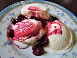 Cherry Bakewell Bliss A Delectably Classic Cherry Bakewell Homemade Ice Cream image 8 jpeg cherry and almond rippled ice cream with cherry coulis drizzled on top with softened chopped cherries on a blue patterned plate frosted fusions