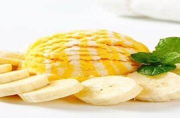 Homemade-Banana-Ice-Cream-Nutritious-and-Delicious-featured-image-200x600w-scoop-of-banana-ice-cream-with-slices-of-banana-circled-around-it-plus-a-sprig-of-fresh-greem-leaves-frosted-fusions