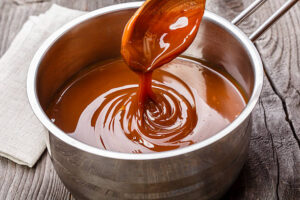 Salivate Over the Irresistible Charm of Salted Caramel Ice Cream Update 190325 image 1 caramel sauce being made in saucepan with wooden spoon Frosted fusions