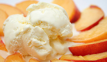 Deliciously Refreshing Homemade Apricot and Thyme Ice Cream Recipe image 1 a scoop of apricot ice cream surrond by slices of fresh apricot white background frosted fusions