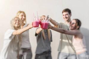 A-Delicious-And-Nutrient-Packed-Berry-Blast-Smoothie-image-7-five-people-all-chinking-their-reddish-pink-smmothies-with-laughter-and-smiles-frosted-fusions