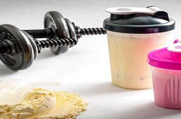 Protein-Shake-Fusions-Creating-Protein-Rich-Low-Fat-Homemade-Ice-Cream-featured-image-200x600w-pair-of-dumbells-two-protein-shakes-and-protein-powder-scattered-with-scoop-frosted-fusions
