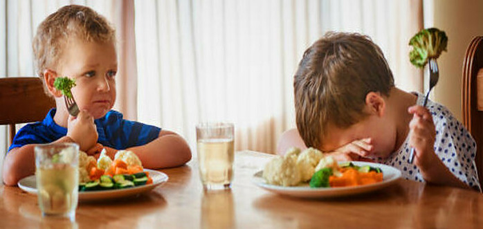 A Delicious And Nutrient-Packed Berry Blast Smoothie image 4 2 young boys looking very forlorn with broccoli on their forks at dinner table one boy with head down on table frosted fusions