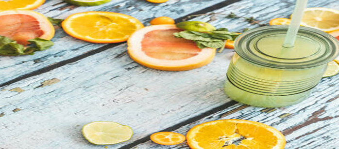 New Year, Fresh Vibes: Nourish Your Body With Healthful Smoothies image 3 glass jar of smoothie with slices of orange lime and lemon scattered on wooden surface frosted fusions