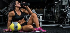 protein-shake-fusions-creating-protein-rich-low-fat-homemade-ice-cream-image-2-woman-in-gym-gear-amongst-gym-equipment-downing-a-protein-shake-frosted-fusions