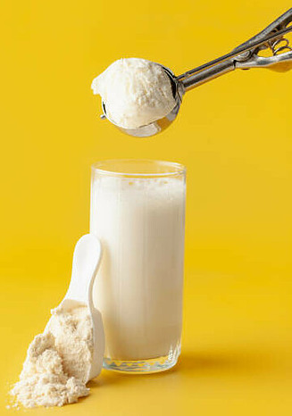 Protein Shake Fusions Creating Protein Rich Low-Fat Homemade Ice Cream image 4 Scoop of ice cream with a glass of milk and a scoop of protein powder yellow background frosted fusions