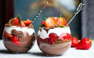 strawberries-and-cream-homemade-parfait-ice-cream-image-3-two-parfaits-in-glasses-with-layers-of-chocolate-strawberries-cream-with-spoons-and-fresh-strawberries-off-to-the-side-frosted-fusions