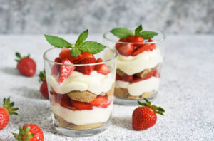 strawberries-and-cream-homemade-parfait-ice-cream-updated Mar25 image 1-strawberry parfait-in-dessert-glasses and-sprig-of-fresh-leaves-frosted-fusions