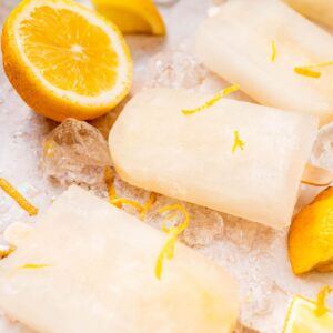 When-Life-Gives-You-Lemons-Make-Homemade-Lemonade-Ice-Lollies-image-4-Lemonade-ice-lollies-with-lemon-zest-and-half-lemaons-in-the-background-frosted-fusions