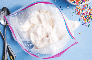 bags-of-fun-learn-how-to-make-homemade-ice-cream-in-a-bag-image-5-open-bag-filled-with-ice-cream-with-sprinkles-and-spoons-to-the-side-frosted-fusions