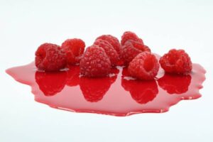 Homemade-Raspberry-Ripple-Ice-Cream-A-Deliciously-Fruity-Treat-image-4-several-vibrant-fresh-raspberries-with-raspberry-sauce-on-white-background-frosted-fusions