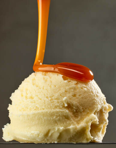 A Delicious And Easy Homemade Butterscotch Ice Cream image 3 single scoop of vanilla ice cream with butterscotch sauce being poured over the top frosted fusions
