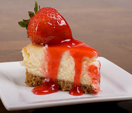 Homemade Strawberry Cheesecake Ice Cream Recipe image 1 slice of classic cheesecake with strawberries and strawberry sauce drizzled over it frosted fusions
