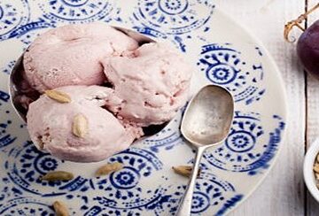 Homemade-Caramelised-Plum-And-Cardamom-Ice-Cream-featured-image-207x620w-plate-of-plum-and-cardamom-ice-cream-with-silver-spoon-with-fresh-plums-and-cardamom-seeds-scattered-frosted-fusions