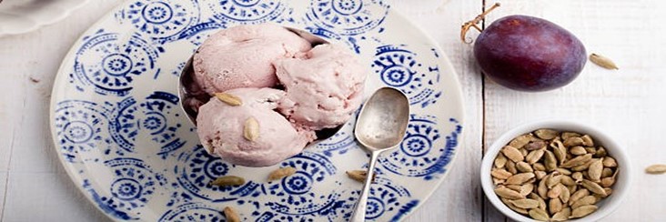 Homemade-Caramelised-Plum-And-Cardamom-Ice-Cream-featured-image-207x620w-plate-of-plum-and-cardamom-ice-cream-with-silver-spoon-with-fresh-plums-and-cardamom-seeds-scattered-frosted-fusions