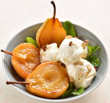 A Warming Homemade Caramelised Pear And Ginger Ice Cream image 4 caramelised pears in white bow with scoops of ice cream scattered with chopped nuts frosted fusions