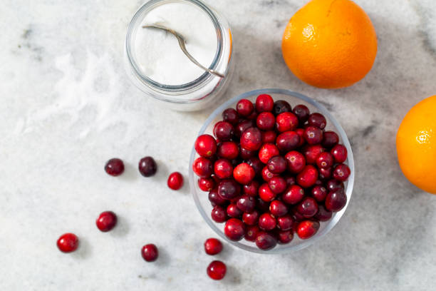 Homemade-Cranberry-Orange-Ice-Cream-Recipe-image-8-top-view-of-oranges-and-pile-of-fresh-cranberries-with-glass-dish-with-sugar-and-spoon-frosted-fusions