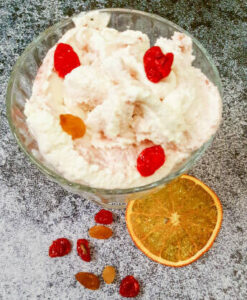 homemade-cranberry-orange-ice-cream-recipe-featured-image-glass-dessert-dish-of-cranberry-and-orange-ice-cream-with-slices-of-oranges-and-fresh-cranberries-scattered-to-the-side-frosted-fusions