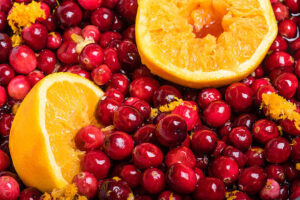 homemade-cranberry-orange-ice-cream-recipe-image-1-a-pile-of-cranberries-and-halves-of-oranges-frosted-fusions