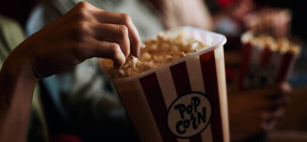 transform-movie-nights-with-delicious-homemade-popcorn-ice-cream-image-1-scene-at-cinema-with-the-focus-on-a-box-of-popcorn-and-light-from-the-front-screen-frosted-fusions