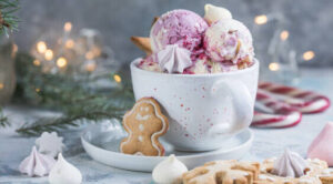 12-irresistible-christmas-ice-cream-recipes-for-your-holiday-table-image-2-scoops-of-ice-cream-in-a-white-bowl-with-gingerbread-men-and-cnady-canes-and-festive-decor-frosted-fusions