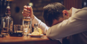 hangover-hacks-how-ice-cream-floats-can-save-your-new-year-s-morning-image-3-man-with-his-head-down-with-a-selection-of-empty-bottles-around-him-frosted-fusions