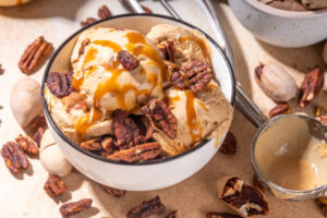 5-Health-Conscious-Homemade-Ice-Cream-Recipes-Using-Natural-Sweeteners-image-2-bowl-of-ice-cream-with-fresh-pecans-and-drizzled-maple-sauce-Frosted-Fusions