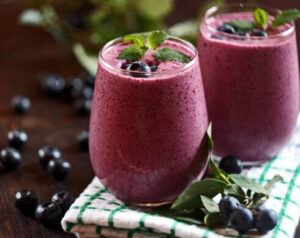 which-smoothie-style-suits-you-best-image-2-glass-of-berry-smoothie-with-berries-scattered-around-frosted-fusions