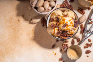 5-Creole-Cajun-Inspired-Ice-Cream-Recipes-To-Jazz-Up-Your-Mardi-Gras-image-3-top-view-of-pecan-ice-cream-with-fresh-pecans-and-ice-cream-scoop-Frosted-fusions