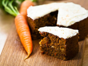 Homemade-Carrot-Cake-Ice-Cream-Recipe-image-1-carrot-cake-with-slice-cut-out-and-fresh-carrots-to-the-side-Frosted-Fusions