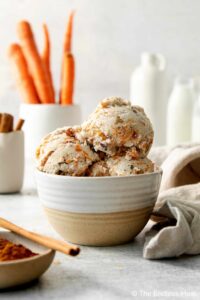 Homemade-Carrot-Cake-Ice-Cream-Recipe-image-2-dish-of-carrot-cake-ice-cream-with-carrots-in-the-background-Frosted-Fusions