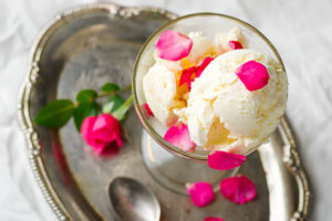 Love-At-First-Scoop-–-Valentines-Ice-Cream-Recipe-Ideas-image-3-top-view-of-rose-petals-scattered-across-a-bowl-of-vanilla-ice-cream-with-ice-cream-scoop-Frosted-Fusions