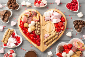 Valentines-Day-Ice-Cream-Dessert-Charcuterie-Board-Ideas-image-3-heart-shapred-wooden-board-filled-with-heart-shaped-cookies-sprinkles-and-dessert-treats-Frosted-Fusions
