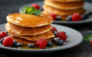 Holy-Crepe-Homemade-Pancake-Ice-Cream-image-3-pile-of-american-style-pancakes-with-syrup-drizzled-over-and-fresh-berries-Frosted-Fusions