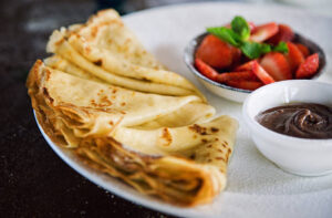 Holy-Crepe-Homemade-Pancake-Ice-Cream-image-4-crepe-style-pancakes-folded-with-dish-of-chocolate-sauce-and-fresh-strawberries-Frosted-Fusions