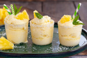 Pina-Colada-Sorbet-Ice-Cream-–-The-Best-Of-Both-Worlds-image-5 three glasses filled with pina colada ice cream with pineapple pieces and fresh leaves Frosted-Fusions