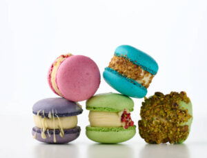 homemade-macaron-ice-cream-recipes-and-ideas-image-8 five ice cream filled macarons different colours some coating in crushed nuts Frosted fusions