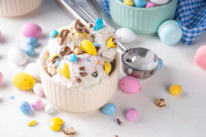 Easy No-Churn Easter Ice Creams – Festive Fun For All Ages image 2 whit dish of mini egg ice cream with mini eggs scattered around Frosated Fusions