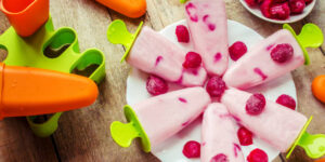 Frozen Yoghurt Lollies For Easter – A Lighter, Healthier Treat image 3 raspberry frozen yoghurt lollies on a plate with fresh raspberries top view Frosted Fusions