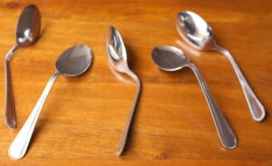 Troubleshooting-Tips-And-Tricks-For-No-Churn-Ice-Cream-image-3-bent-spoons-on-a-wooden-surface-Frosted-Fusions