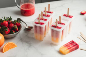 Naturally Sweet Sorbets For Summer – Healthy, Easy Dessert Ideas image 2 lollipop sorbets in moulds with fresh orange and strawbs Frosted Fusions