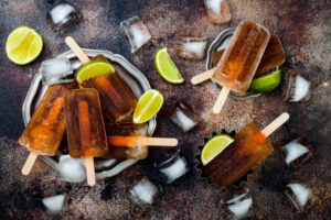 Cocktail-Inspired Ice Creams, Sorbets & Ice Lollies For Long Hot Summer Days Image 2 rum and coke ice lollies in dish with ice limes Frosted Fusions