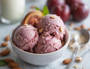 Vegan Desserts - Exciting, Healthy & Unique Plant-Based Ice Cream Recipes image 3 roasted plum and almond ice cream in a bowl with fresh plums in the background Frosted Fusions