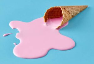How-To-Stop-Homemade-Ice-Cream-From-Melting-Too-Fast-image-1-ice-cream-waffle-cone-with-pink-ice-cream-puddle-of-melted-ice-cream-blue-background-Frosted-Fusions